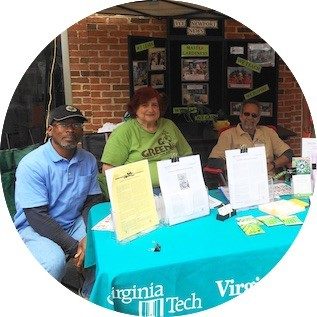 master gardeners sit at help desk with pamphlets on table in front of them