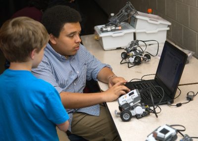 Maker coach Instructs student on the programming of robots.