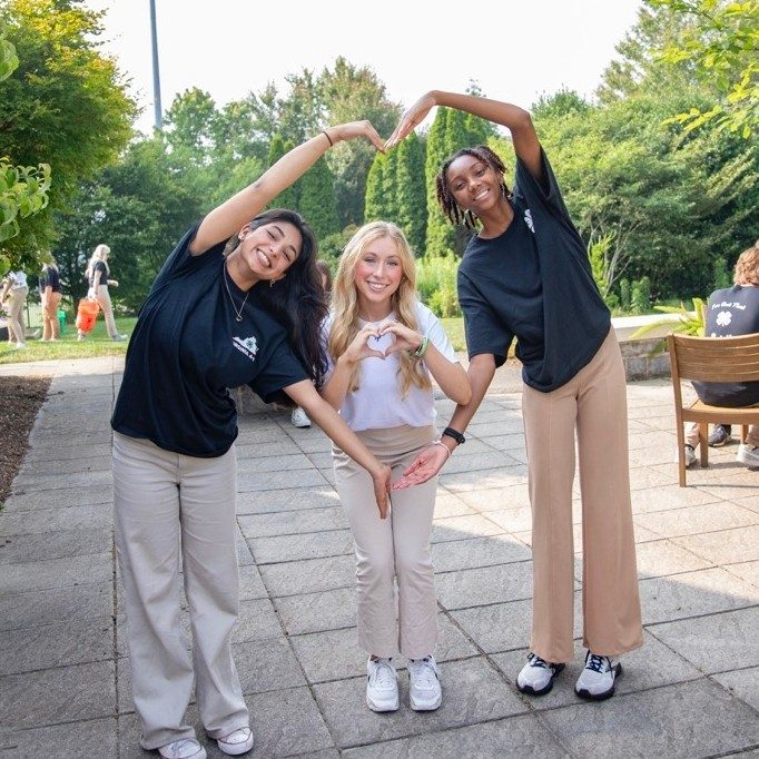 Three 4-H youths make a heart with their arms
