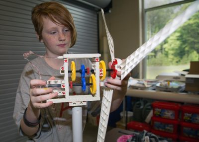 Student inspects the gears on a recently built windmill.