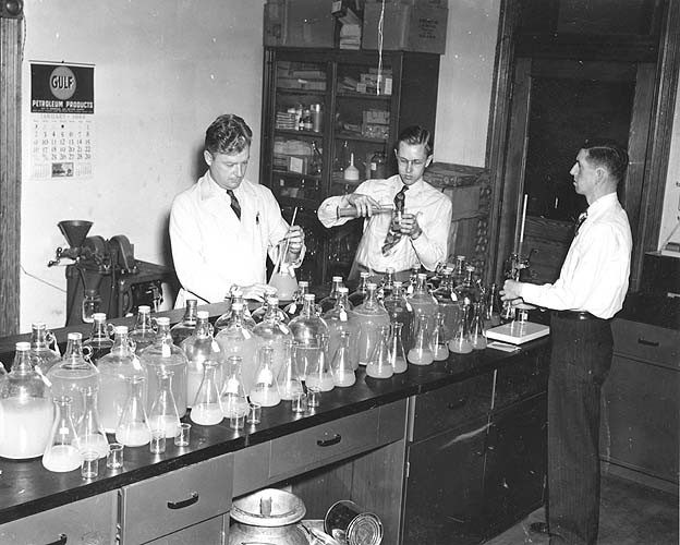 Men work in a lab with jars and beakers in the 1940s.
