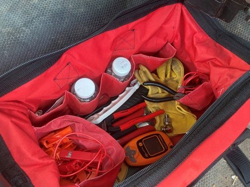 A red and black canvas case full of tools.